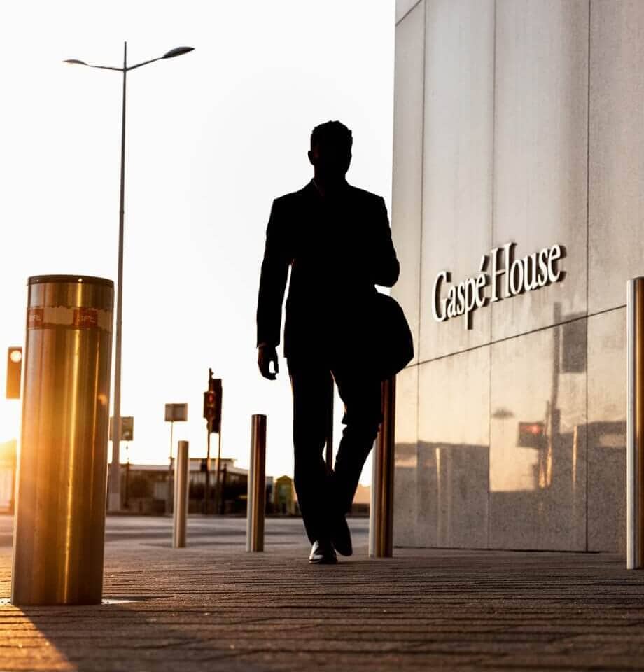 Businessman walking by Jersey International Finance Centre buildings