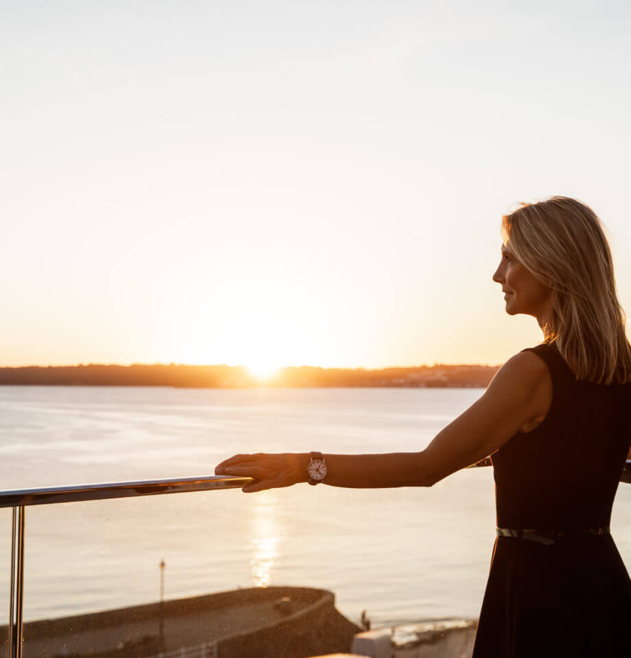 Sunset with businesswoman on office balcony overlooking the sea